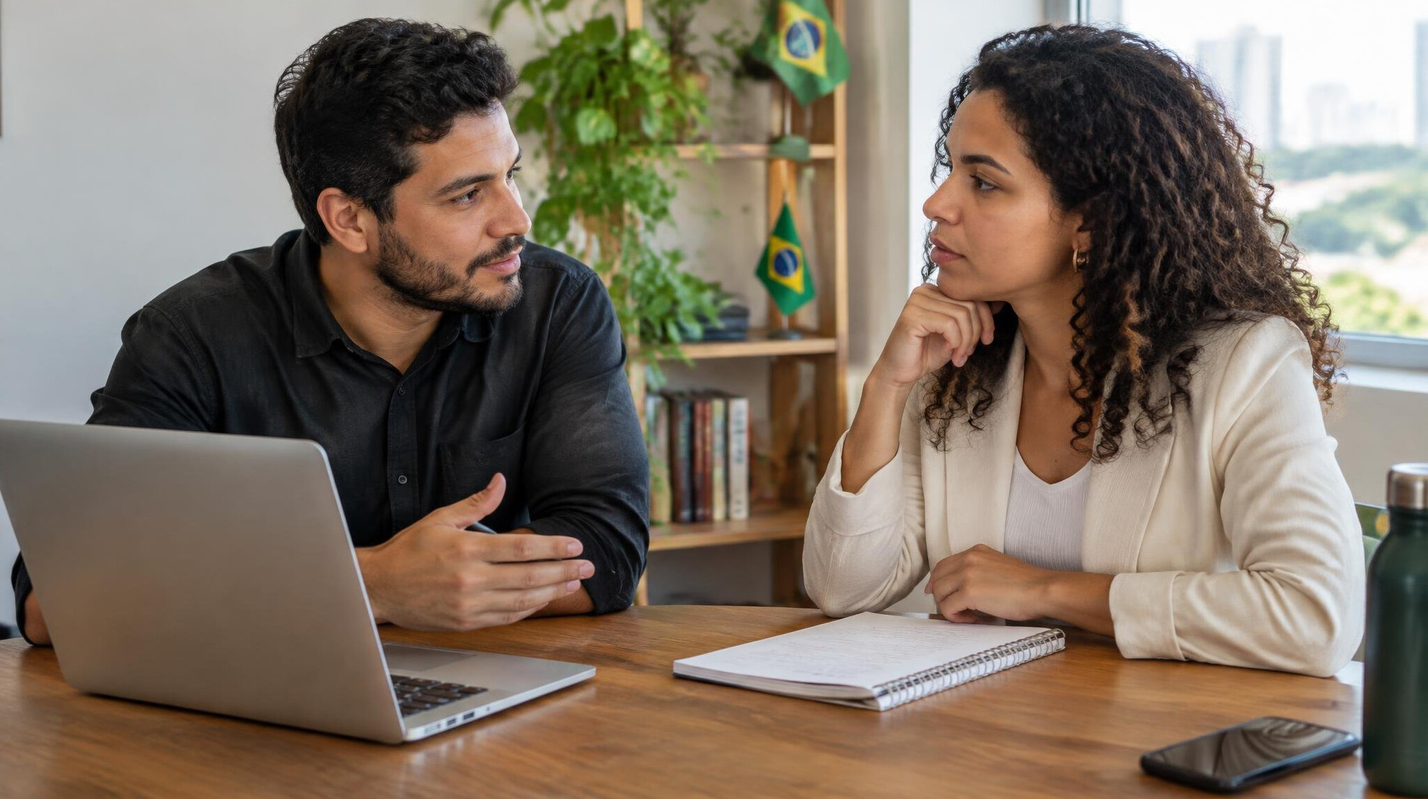 Two colleagues collaborating and talking over a laptop in an office